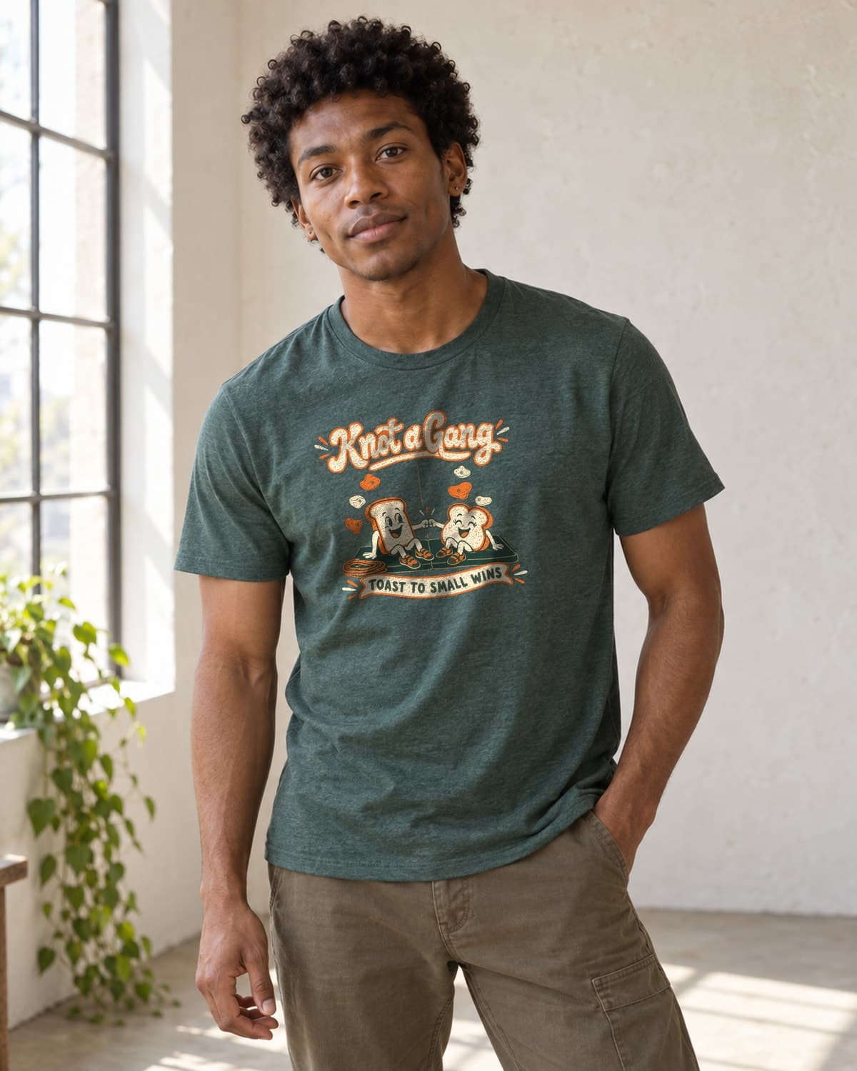 A man wearing the Heather Forest Green Toast to Small Wins T-shirt in natural studio light.
