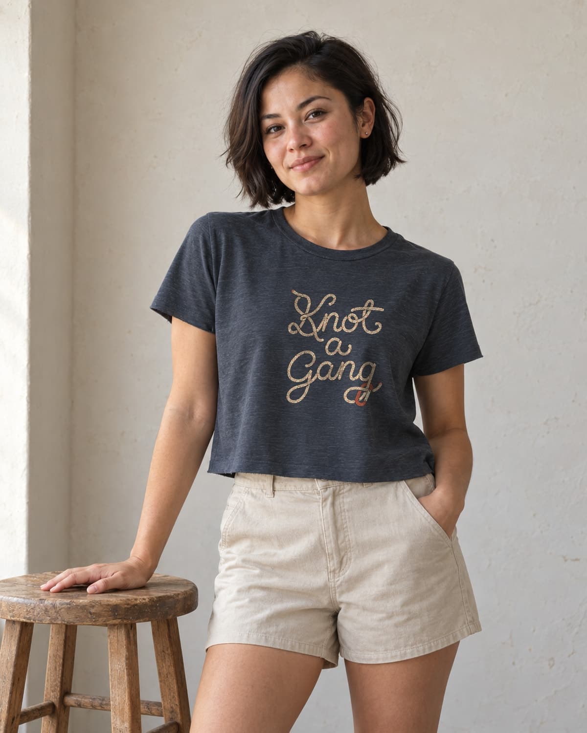 A woman wearing the Antique Denim Braided Script and a Clip crop top in natural studio light.