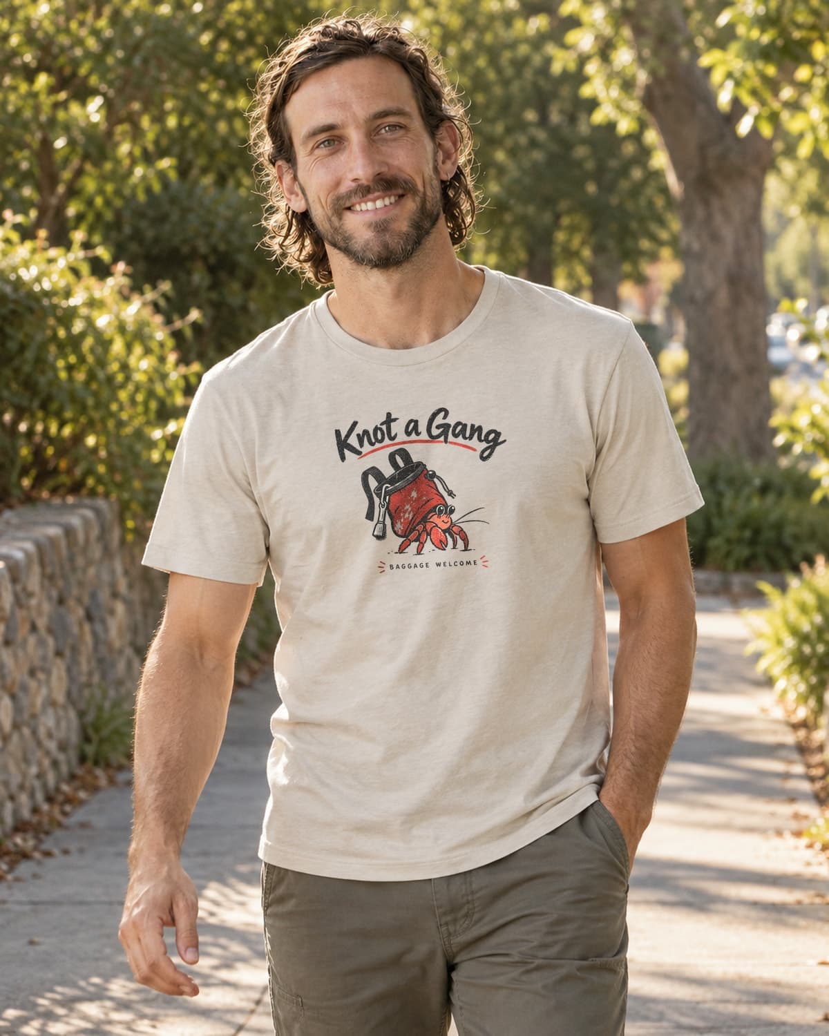 A man wearing the Sand Baggage Welcome T-shirt in a relaxed lifestyle setting.