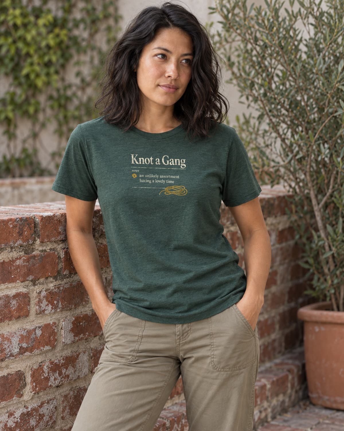 A woman wearing the Heather Forest Green A Collective Noun T-shirt in a relaxed lifestyle setting.