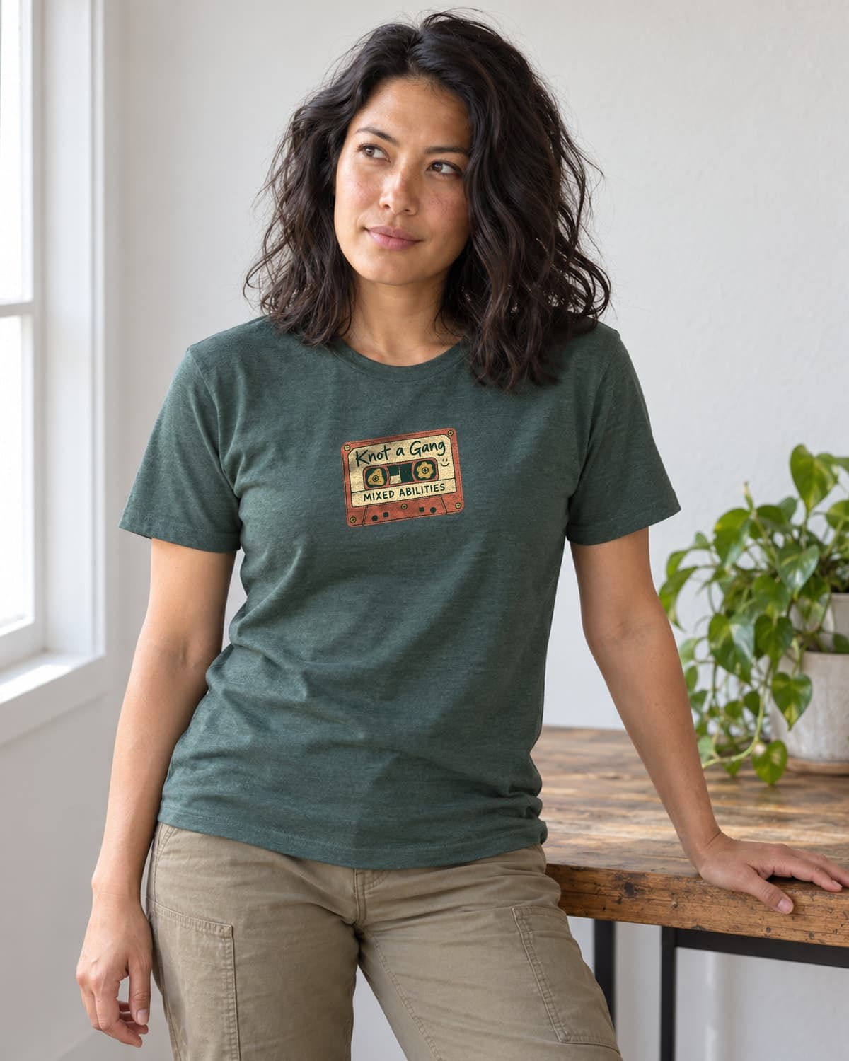 A woman wearing the Heather Forest Green Mixed Abilities Mixtape T-shirt in natural studio light.