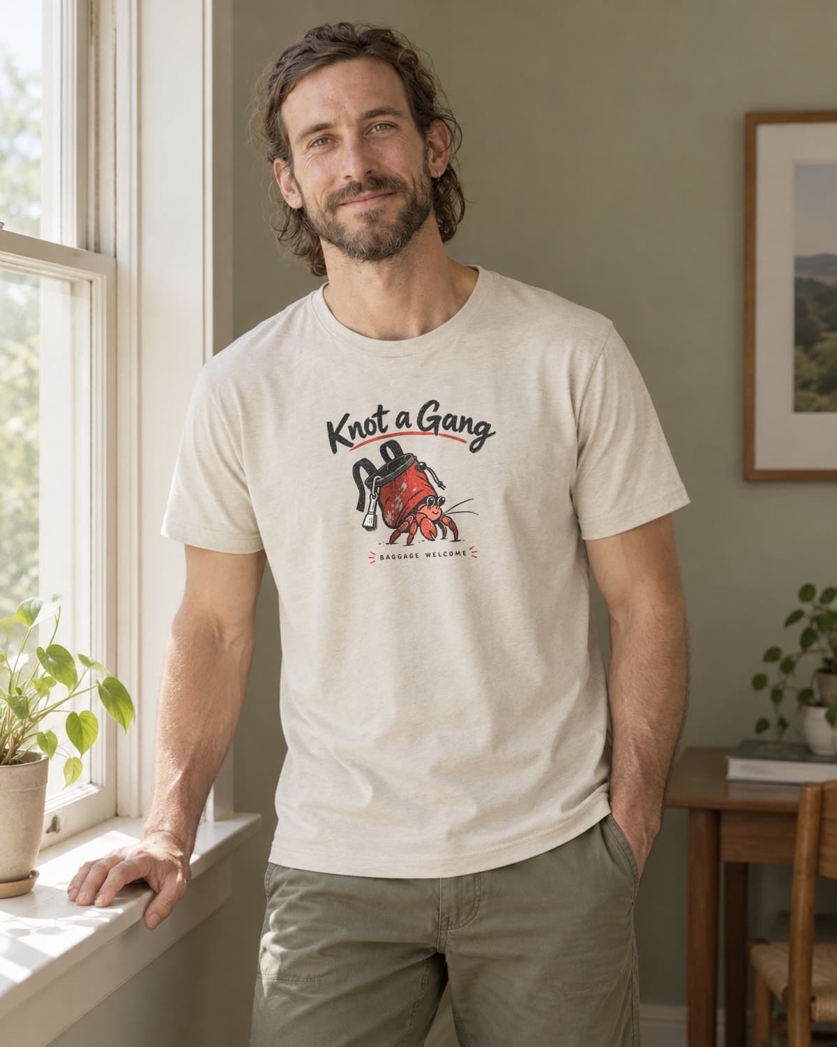 A man wearing the Sand Baggage Welcome T-shirt in natural studio light.