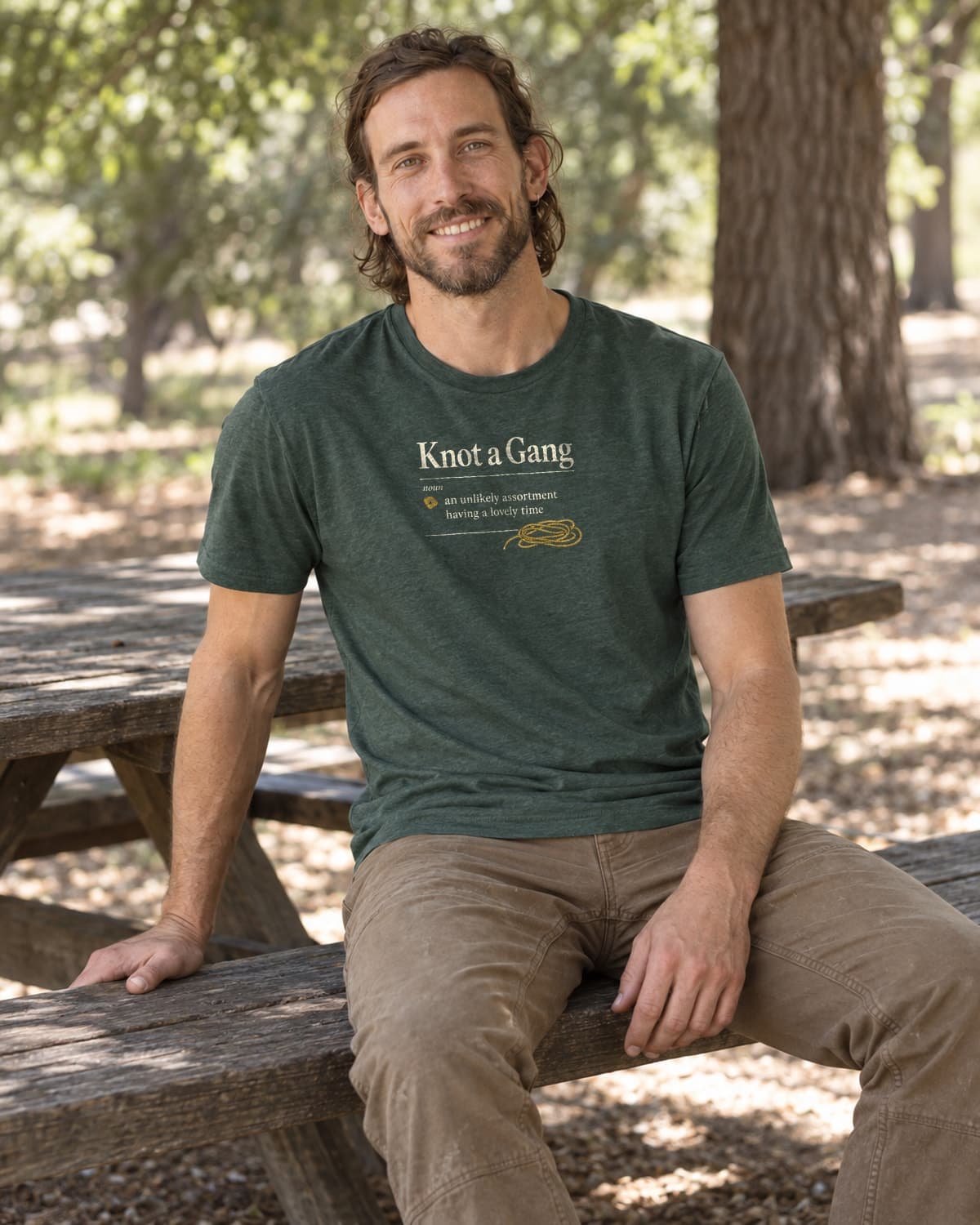 A man wearing the Heather Forest Green A Collective Noun T-shirt in a relaxed lifestyle setting.