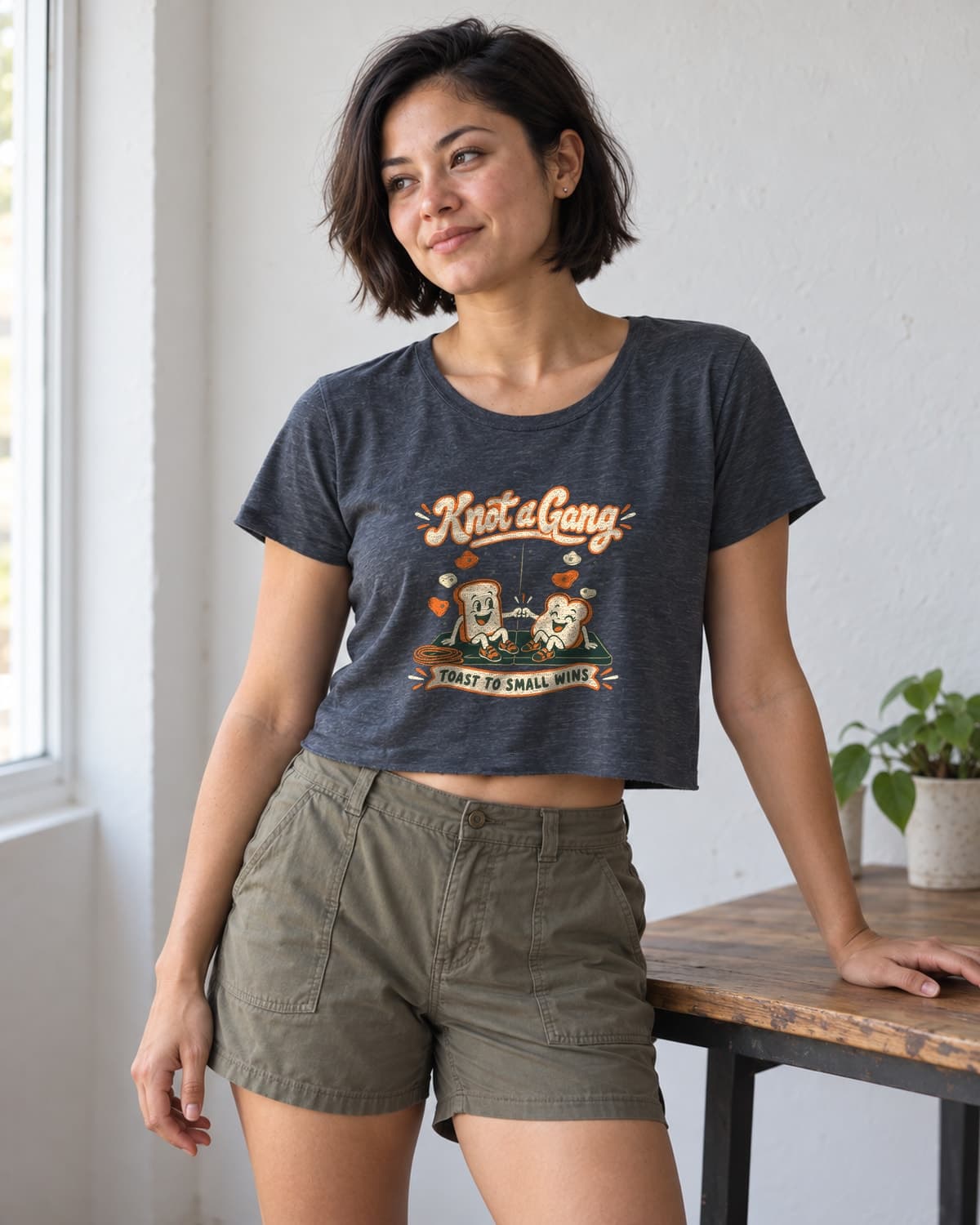 A woman wearing the Antique Denim Toast to Small Wins crop top in natural studio light.