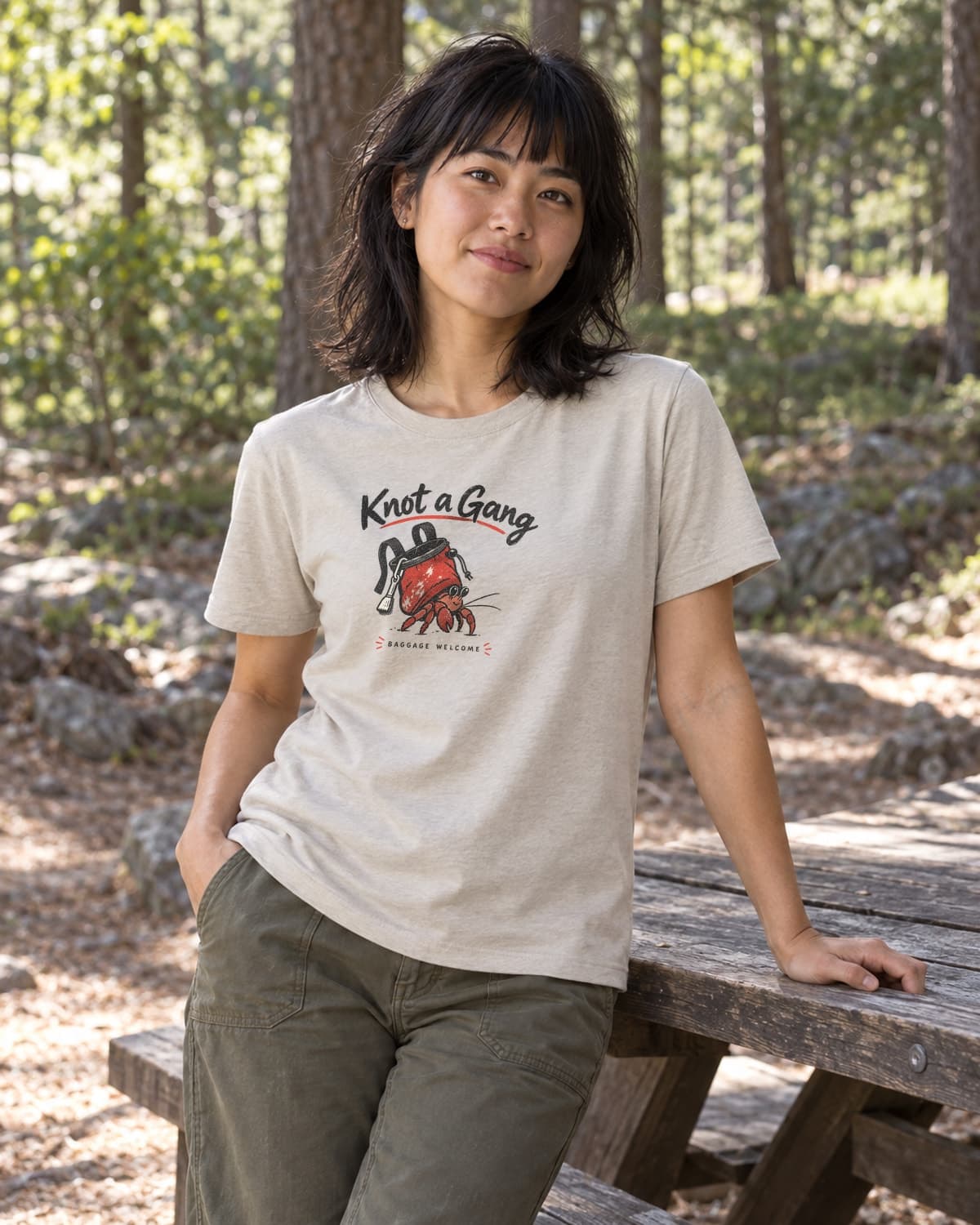 A woman wearing the Sand Baggage Welcome T-shirt in a relaxed lifestyle setting.