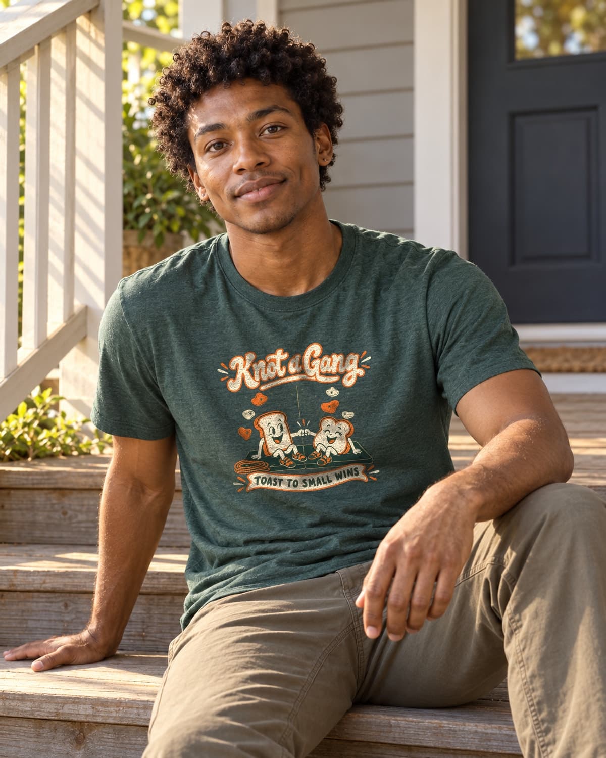 A man wearing the Heather Forest Green Toast to Small Wins T-shirt in a relaxed lifestyle setting.