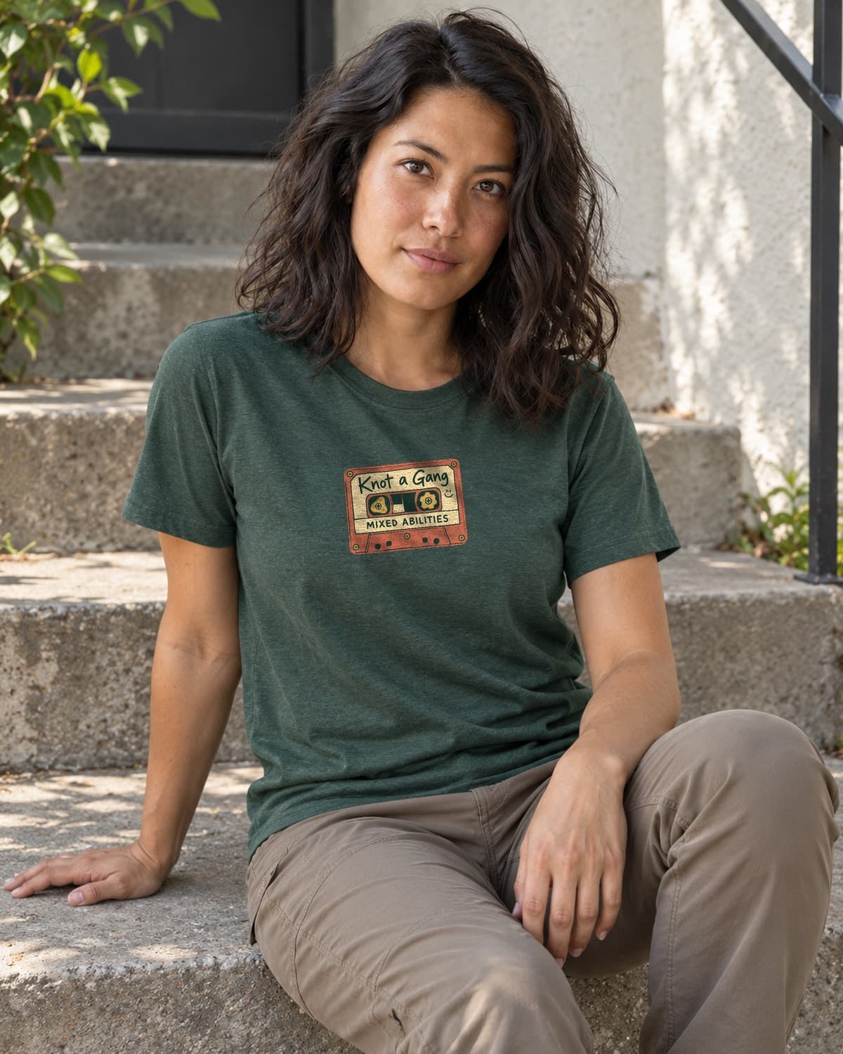 A woman wearing the Heather Forest Green Mixed Abilities Mixtape T-shirt in a relaxed lifestyle setting.